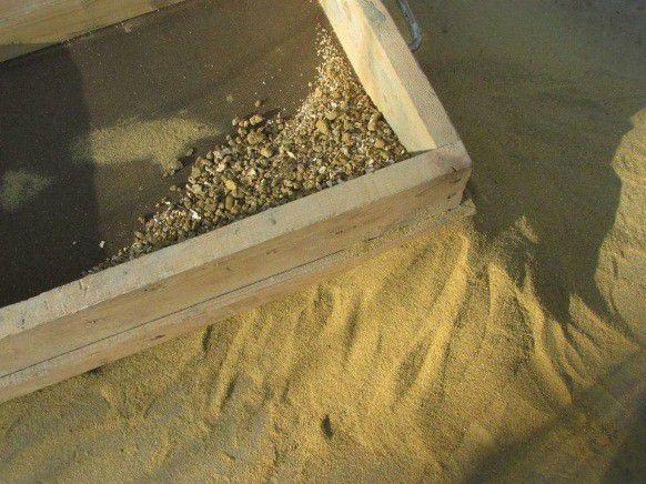 Sand mit einem Sieb sieben